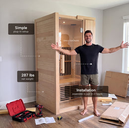 Man standing beside the 1-Person Infrared Hemlock Sauna with feature callouts