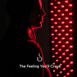 Woman next to the red light panel of the 3-Person Red Light + Full Spectrum Hemlock Sauna