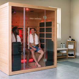 Two people sitting inside the 3-Person Red Light + Full Spectrum Hemlock Sauna