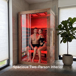 Couple inside the 2-Person Red Light + Full Spectrum Hemlock Sauna next to a plant