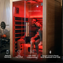 Couple inside the 2-Person Red Light + Full Spectrum Hemlock Sauna with red light on, feature icons