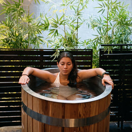 Woman sitting in the 1-Person Cedar Ice Bath in a garden